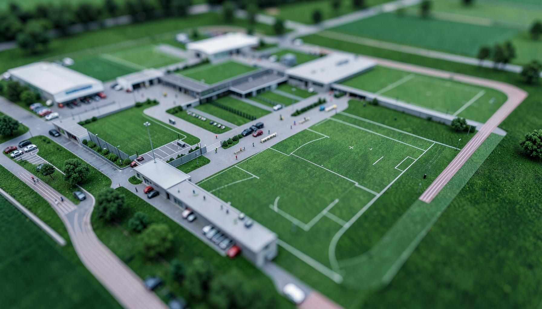 Aerial rendering of a large sports and training facility complex with buildings, fields, a parking lot, and a running track